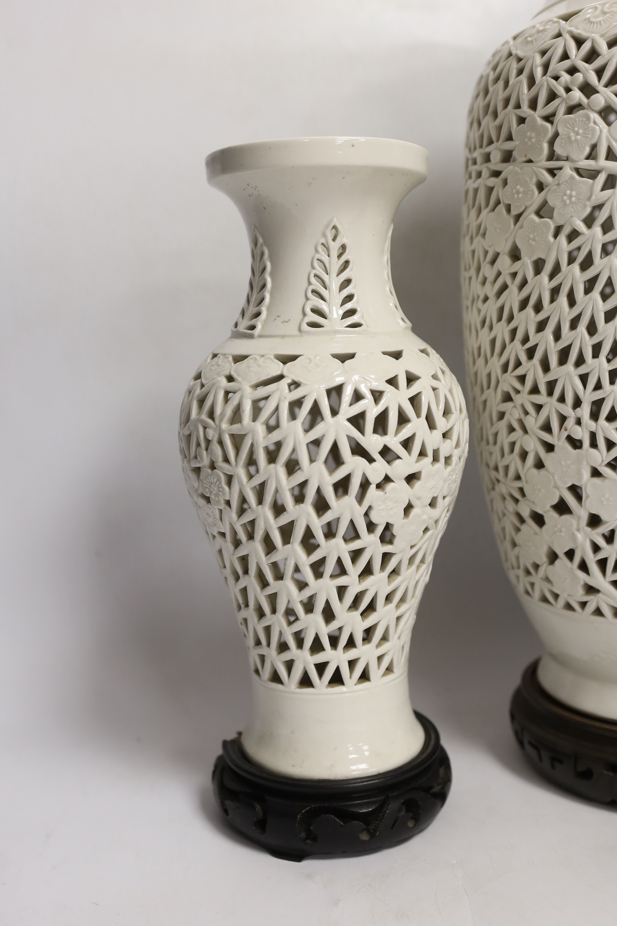 Two Chinese blanc de chine reticulated vase/lamps, on carved stands, largest 40cm high